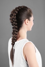 Woman with braided hair on grey background