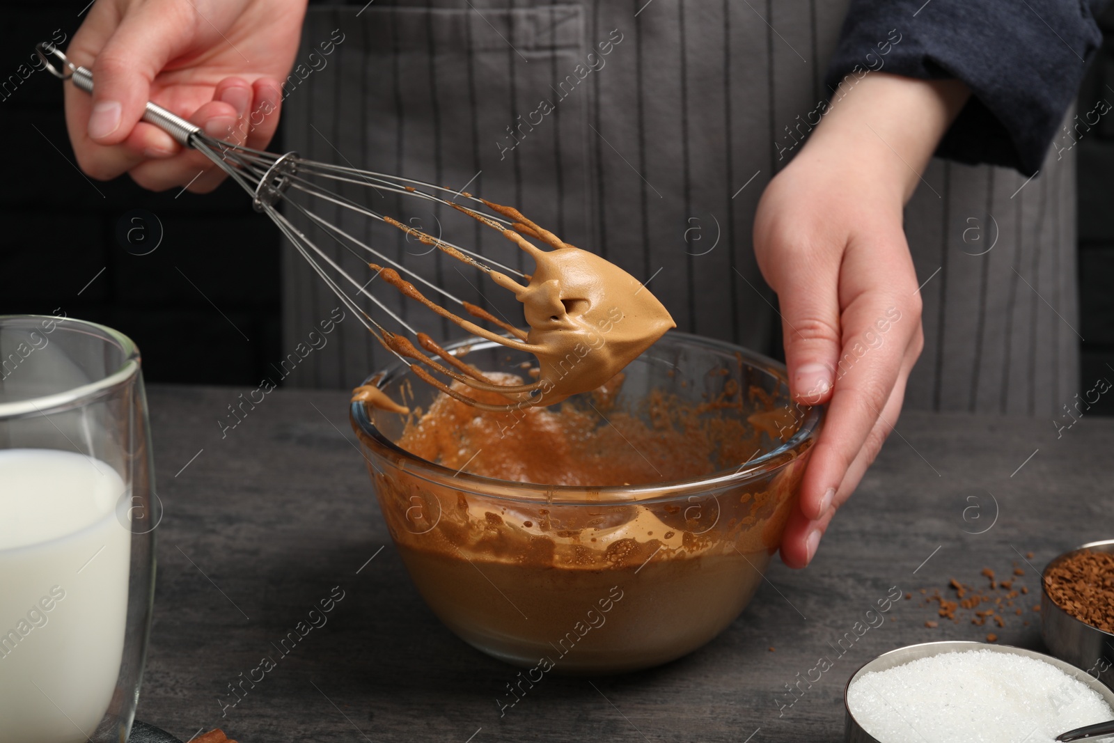 Photo of Woman whipping cream for dalgona coffee at grey table, closeup