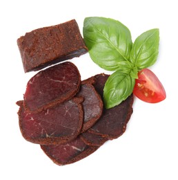 Photo of Delicious dry-cured beef basturma with basil and tomato on white background, top view