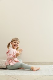 Photo of Cute little girl drawing on beige wall indoors, space for text. Child`s art