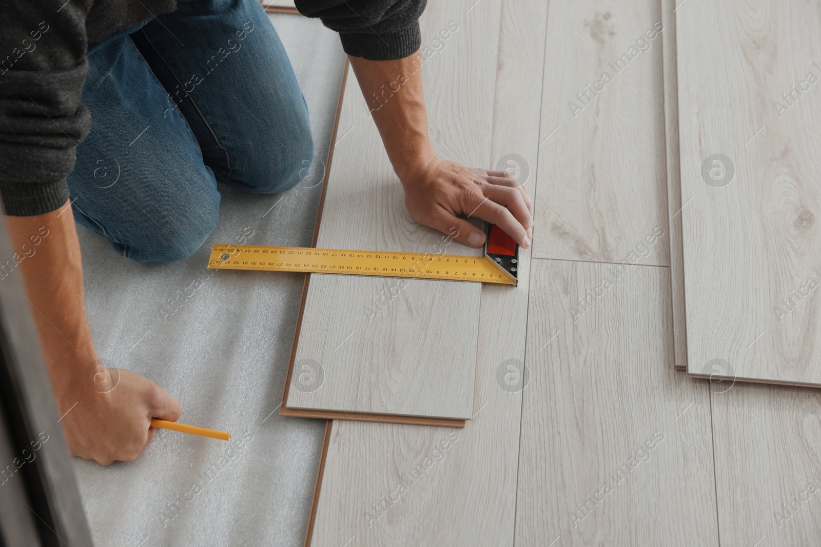 Photo of Worker installing new laminate flooring in room, closeup