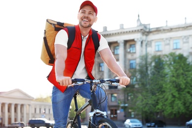 Male courier on bicycle delivering food in city