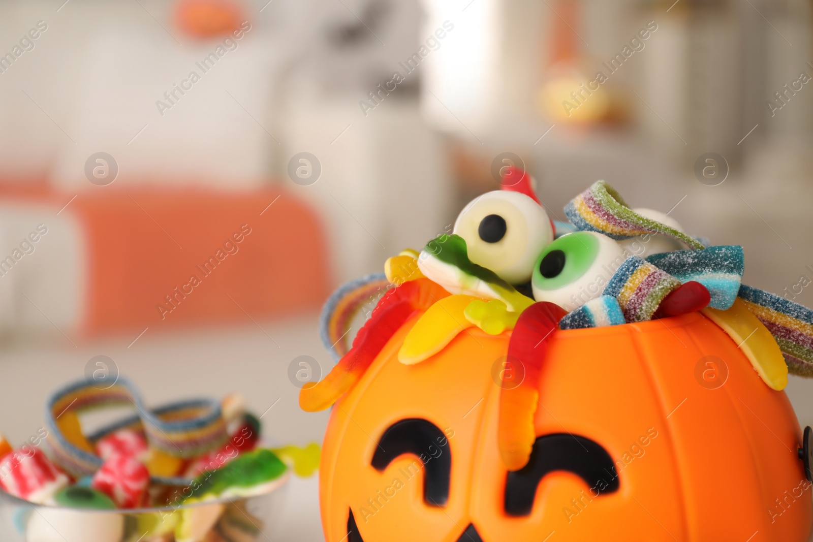 Photo of Halloween trick or treat bucket with different sweets indoors, closeup