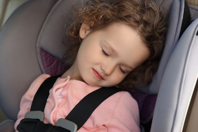 Cute little girl sleeping in child safety seat inside car