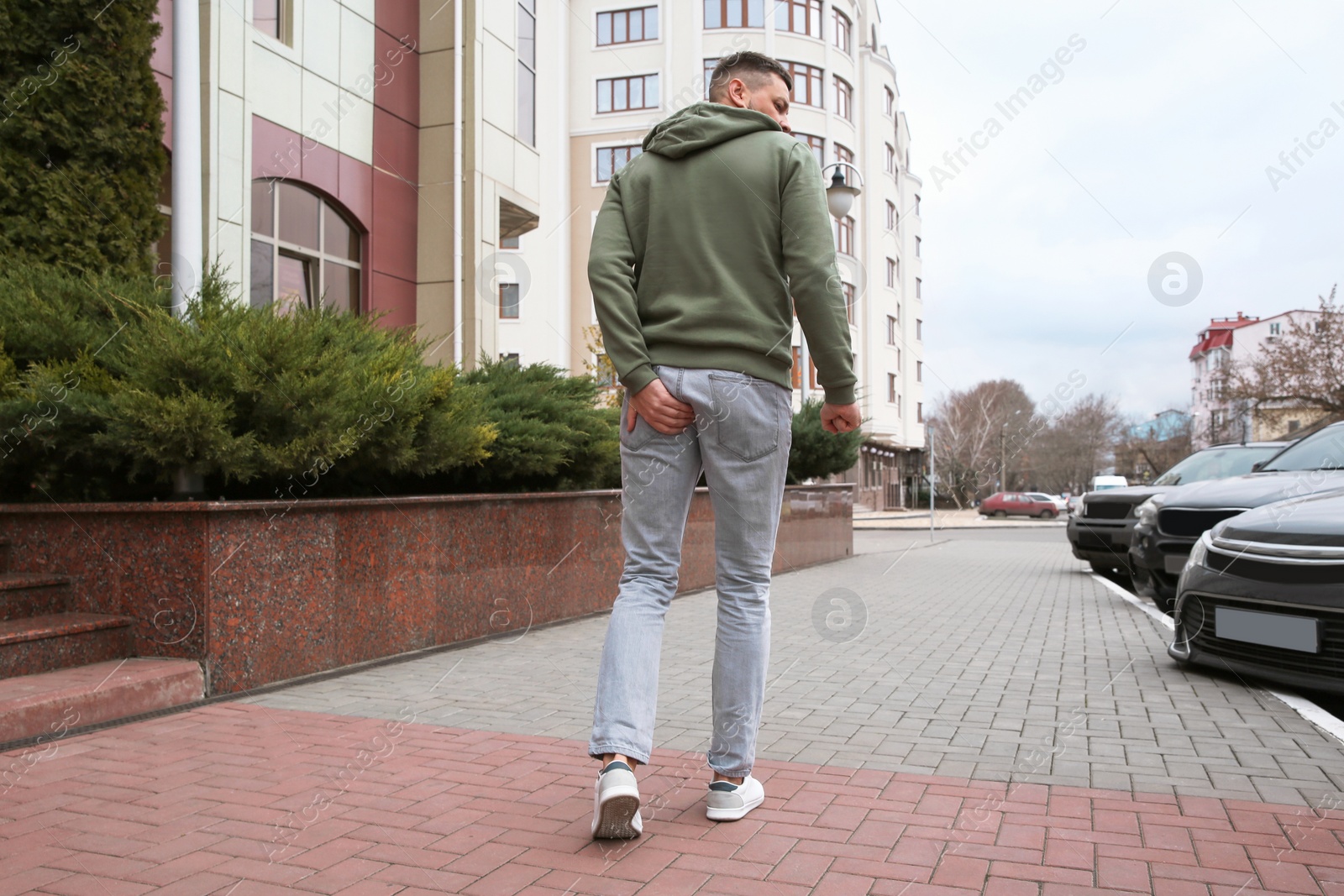 Photo of Man suffering from hemorrhoid pain outdoors, back view