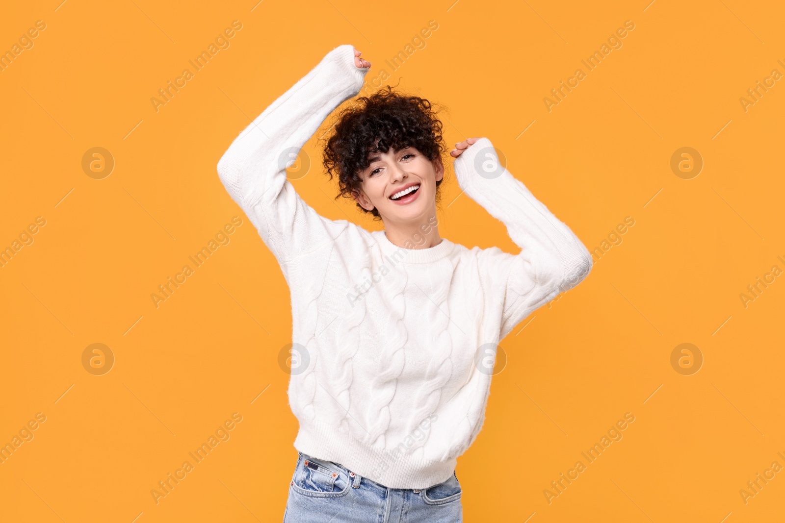 Photo of Happy young woman in stylish white sweater on yellow background