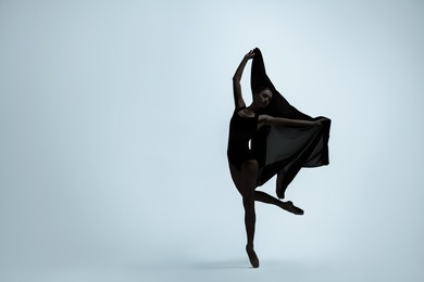 Image of Beautiful ballerina with black veil dancing on light background, space for text. Dark silhouette of dancer