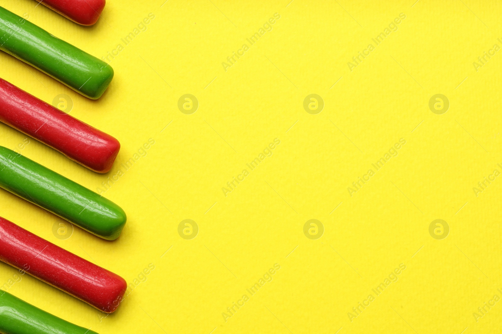 Photo of Many tasty bubble gums on yellow background, flat lay. Space for text