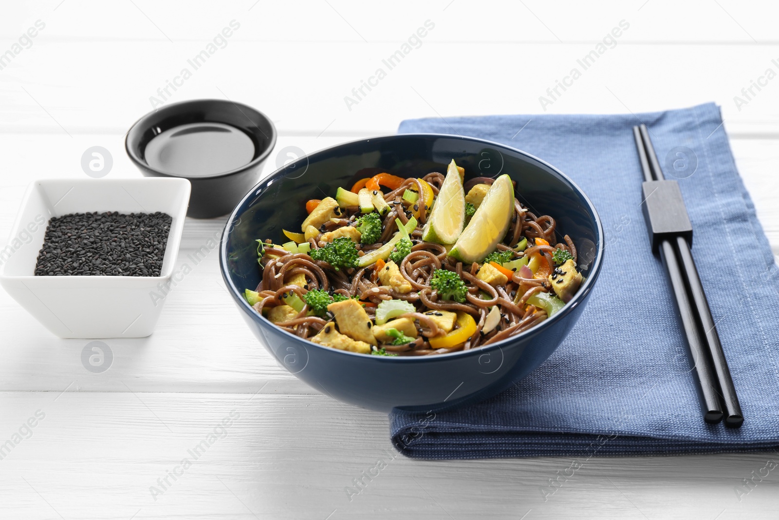 Photo of Stir-fry. Delicious cooked noodles with chicken and vegetables in bowl served on white wooden table