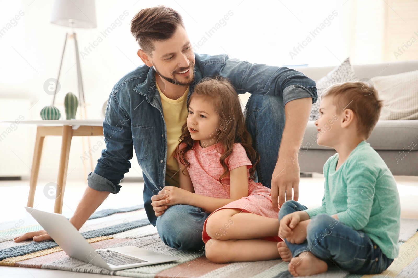 Photo of Young man using laptop with children at home. Happy family