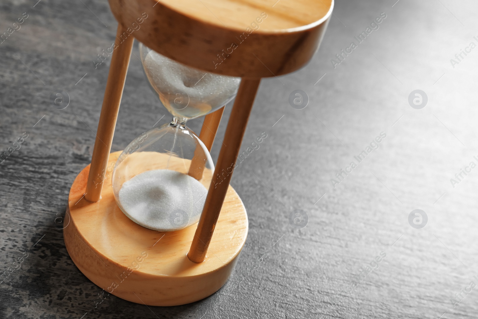 Photo of Hourglass with flowing sand on table. Time management