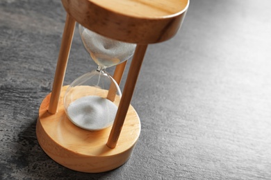 Photo of Hourglass with flowing sand on table. Time management