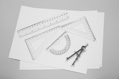 Flat lay composition with different rulers and compass on light grey background