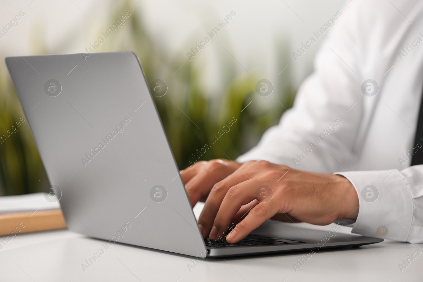 Photo of Man using modern laptop at desk in office, closeup