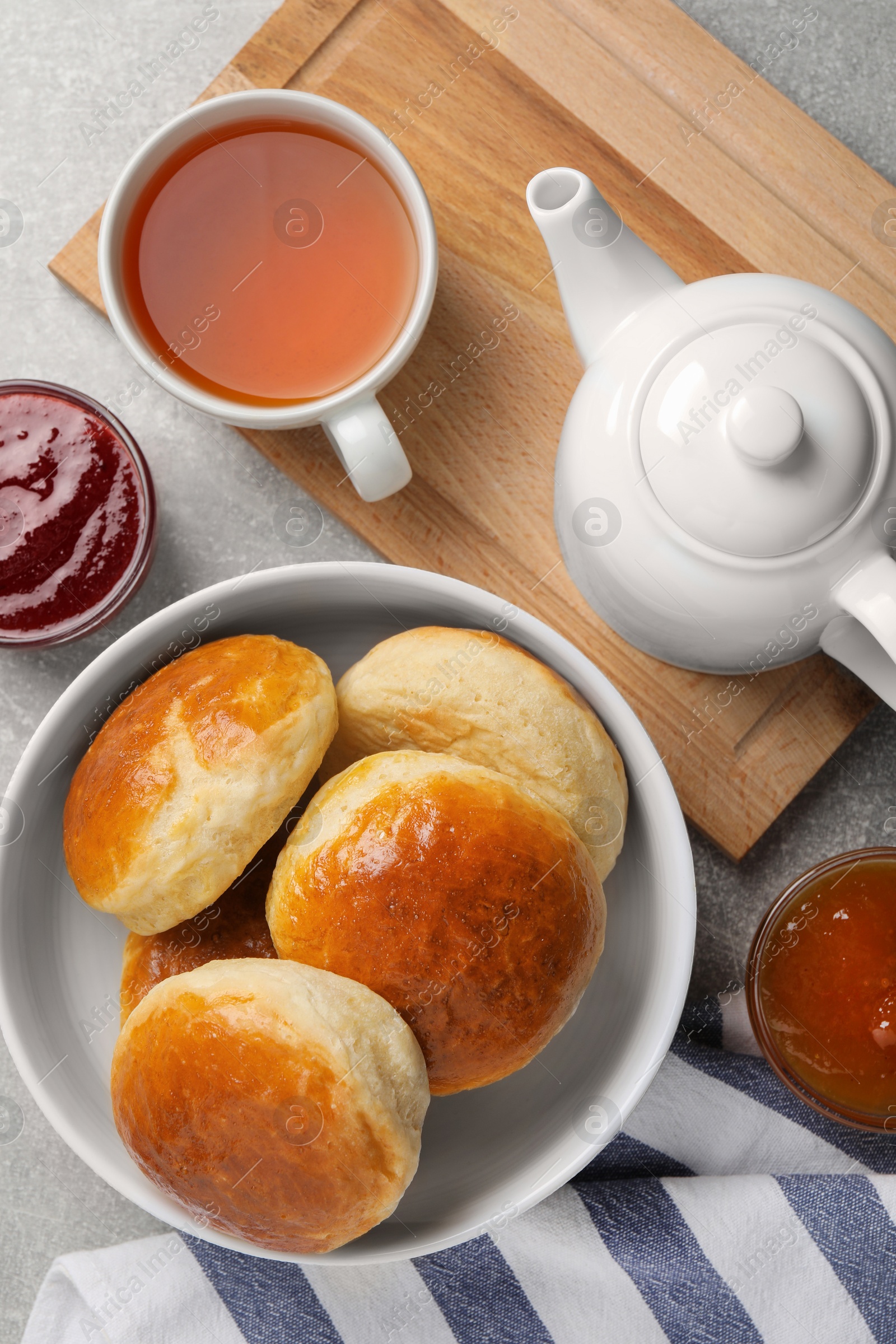 Photo of Tasty scones prepared on soda water, jam and tea on grey marble table, flat lay