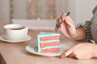 Woman eating fresh delicious birthday cake at table, closeup