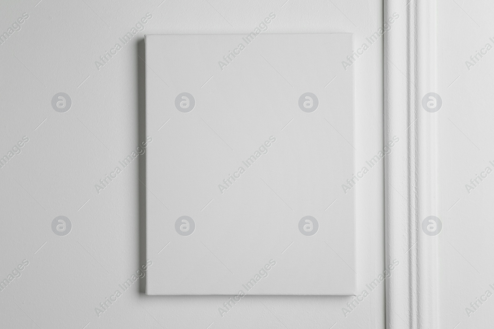 Photo of Blank canvas hanging on white wall, space for text