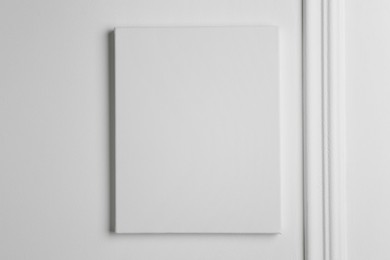 Photo of Blank canvas hanging on white wall, space for text