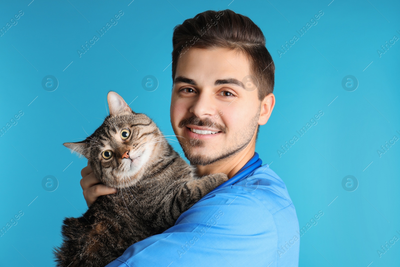 Photo of Veterinarian doc with cat on color background