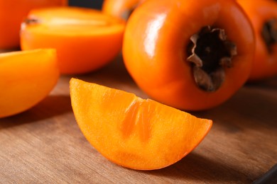 Photo of Delicious ripe persimmons on wooden table, closeup