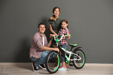 Portrait of parents and their daughter with bicycle near color wall