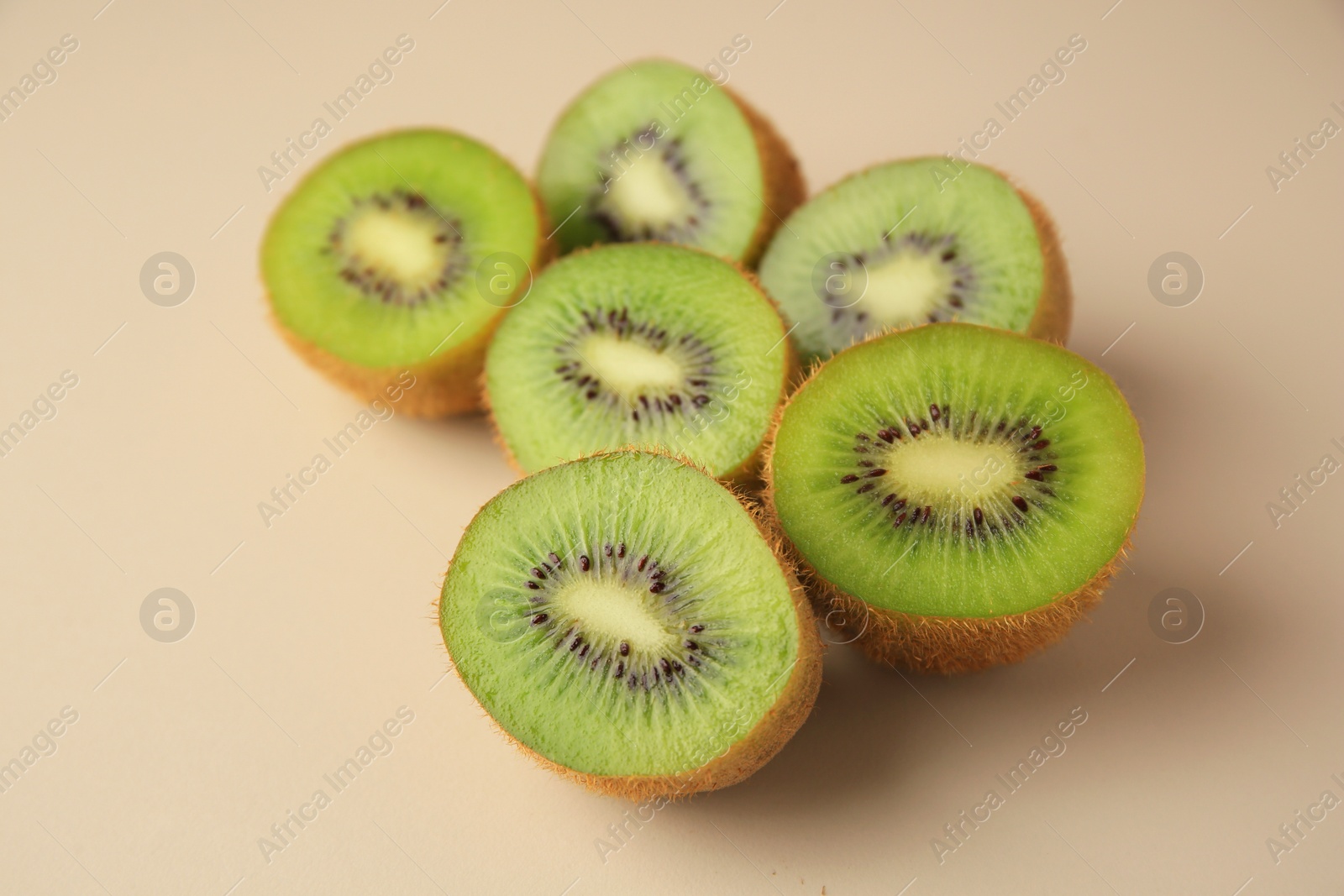 Photo of Halves of fresh kiwis on beige background