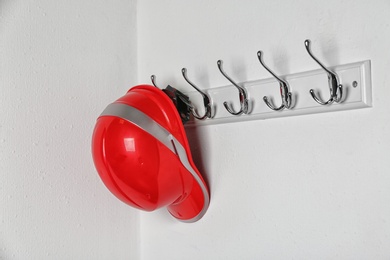Hard hat hanging on white wall. Safety equipment