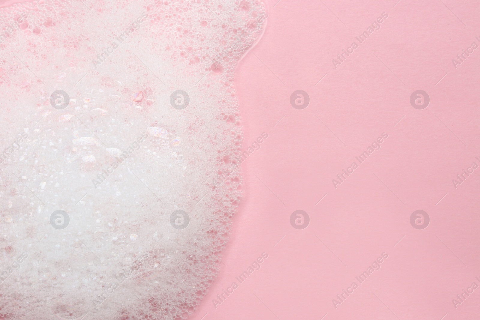 Photo of Fluffy bath foam on pink background, top view. Space for text