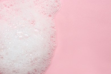 Photo of Fluffy bath foam on pink background, top view. Space for text