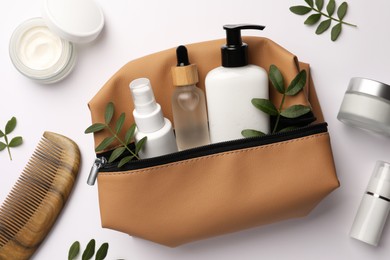 Photo of Preparation for spa. Compact toiletry bag with cosmetic products, comb and twigs on white background, top view