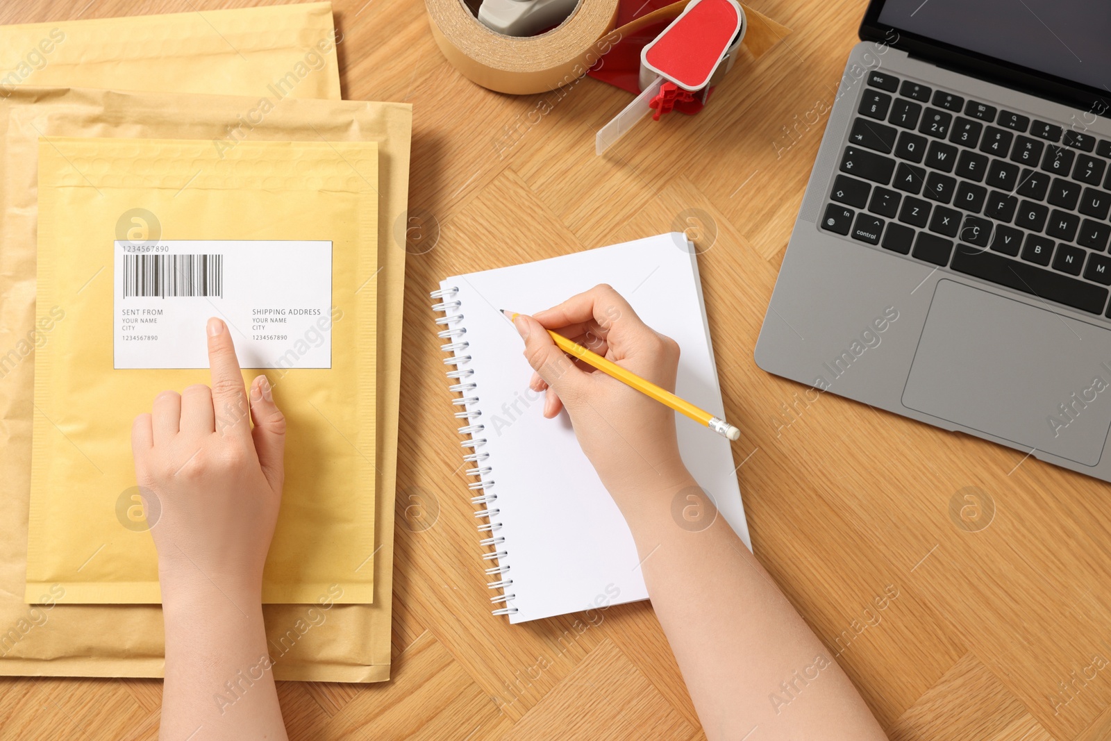 Photo of Woman writing in notebook at wooden table, top view. Online store