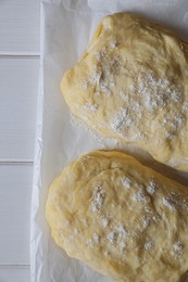 Photo of Raw dough for ciabatta and flour on white wooden table, top view