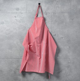 Photo of Clean red striped apron on grey tiled wall. Space for text