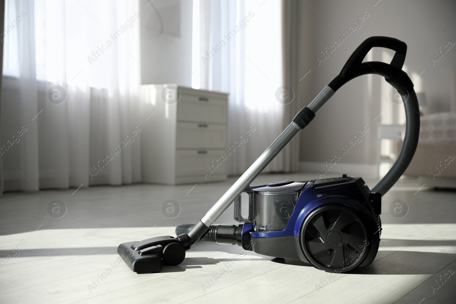 Photo of Modern vacuum cleaner on floor in bedroom