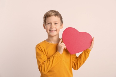 Photo of Cute boy holding heart shaped box on white background