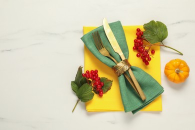 Photo of Autumn table setting. Cutlery, napkins, viburnum berries and pumpkin on white marble background, flat lay with space for text