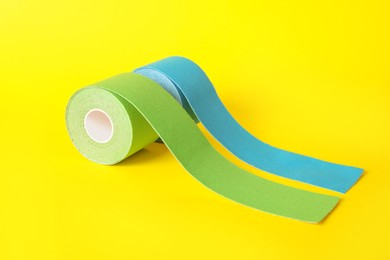 Photo of Bright kinesio tape in rolls on yellow background