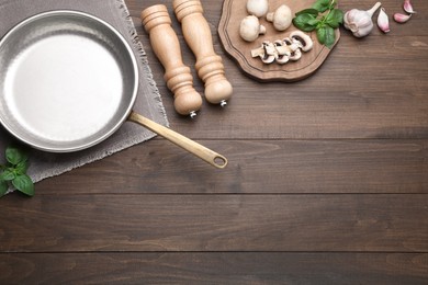 Photo of Flat lay composition with empty frying pan and fresh products on wooden table, space for text