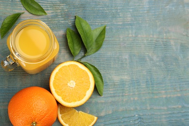 Photo of Delicious orange juice and fresh fruits on light blue wooden table, flat lay. Space for text