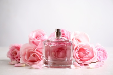 Bottle of perfume and beautiful roses on light table