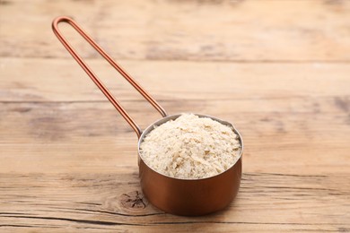 Metal small saucepan with brewer`s yeast flakes on wooden table