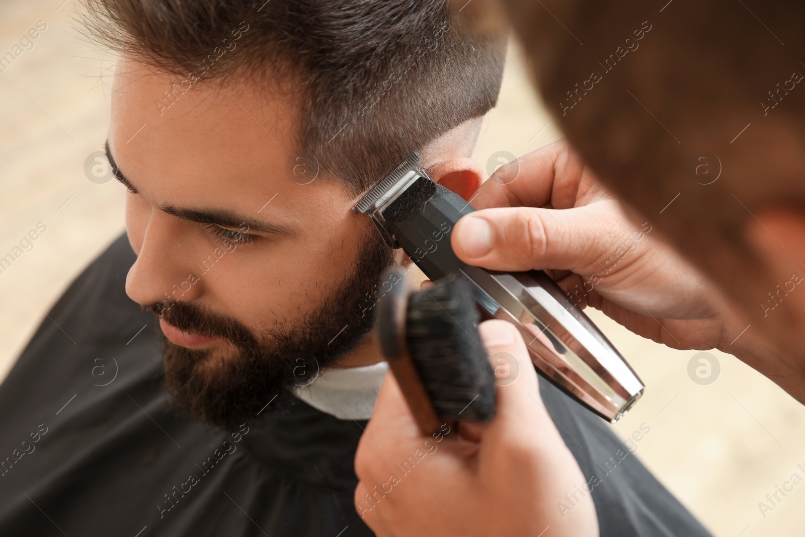 Photo of Professional hairdresser working with client in barbershop, closeup