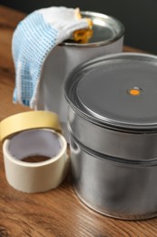 Photo of Cans of orange paint and renovation equipment on wooden table, closeup