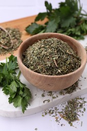Photo of Dried parsley and fresh leaves on white table, closeup