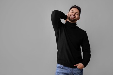 Photo of Happy man in stylish black sweater on grey background