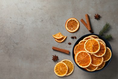 Dry orange slices, cinnamon sticks and anise stars on grey table, flat lay. Space for text