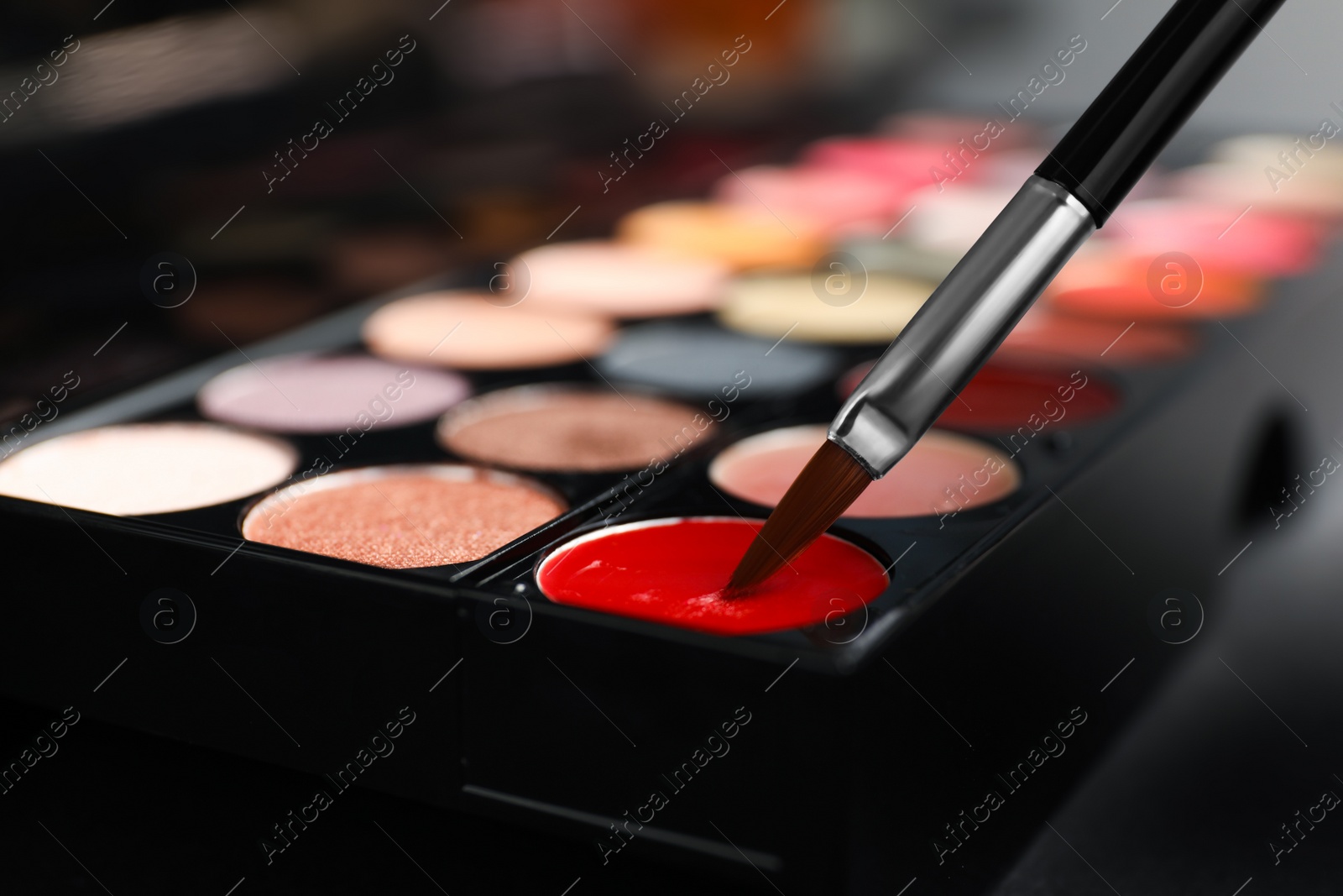 Photo of Colorful lip palette with brush on dark background, closeup
