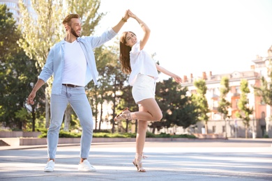 Lovely young couple dancing together outdoors on sunny day