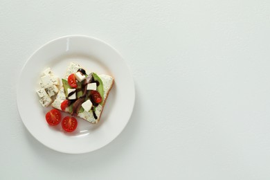 Delicious sandwich with anchovies, cheese and tomato on white table, top view. Space for text