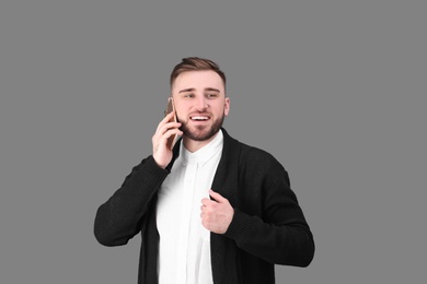 Photo of Portrait of confident young man with mobile phone on color background